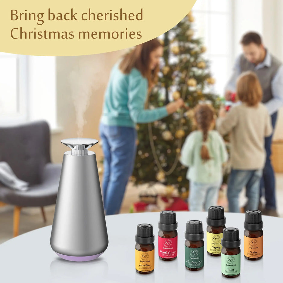 diffuser oil bottles with a diffuser on a table, with a family decorating a Christmas tree in the background.